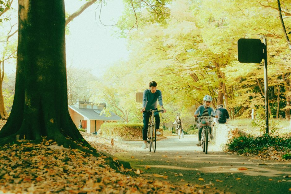 父と娘が晴れた秋の日に風景の美しい公園で自転車を楽しんでいます。