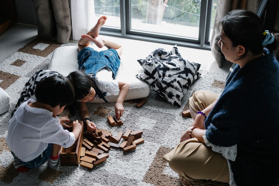 子供たちが祖母と一緒に木のブロックで遊んでいる、居心地の良いリビングルームの設定。