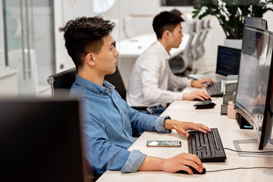現代的なオフィス環境でコンピュータを使って仕事をする若手プロフェッショナルたち、タスクに集中しています。